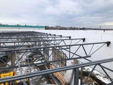 Steel framework of a construction site under a cloudy sky, showing progress on a building.
