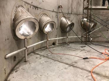 Interior view of industrial site featuring four metal light fixtures on a concrete wall.