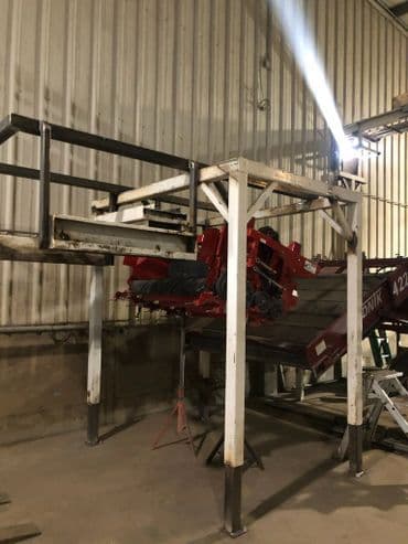 Industrial machine setup in a warehouse, featuring red equipment on a metal platform.