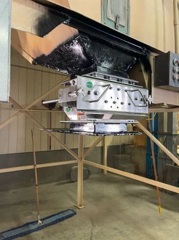 Industrial equipment with a hopper and control panel in a large warehouse setting.