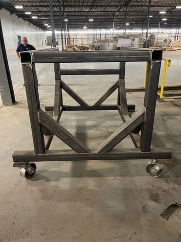 Industrial metal cart on wheels in a warehouse environment, showcasing sturdy construction.