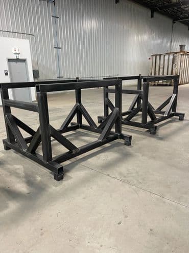 Industrial metal manufacturing workbenches on a concrete floor in a warehouse setting.