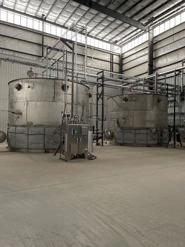 Industrial storage tanks in a modern facility with metal framework and concrete flooring.