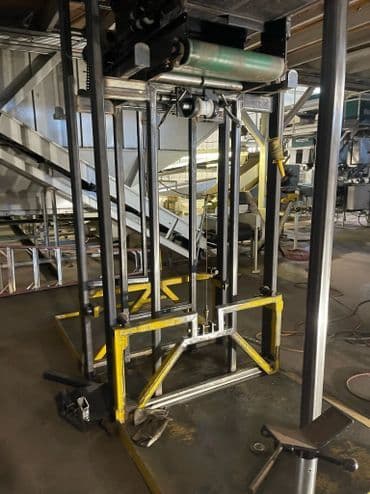 Industrial lifting equipment with metal frame and rollers in a warehouse setting.