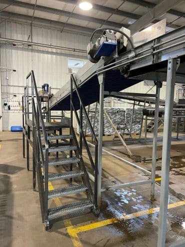 Metal conveyor system with stairs in an industrial facility for efficient material handling.