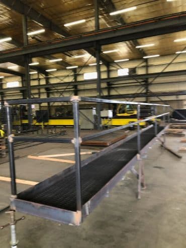 Industrial scaffolding in a spacious warehouse with metal framing and wooden planks.