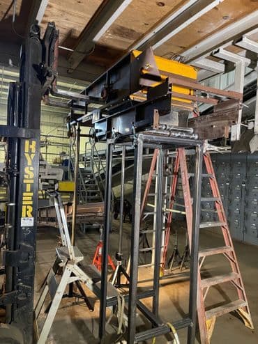 Industrial equipment setup with Hyster forklift, ladders, and machinery in warehouse.