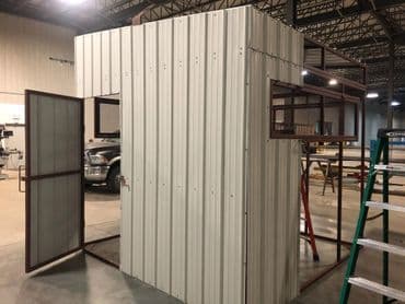 Metal storage structure with open doors in a spacious warehouse setting.