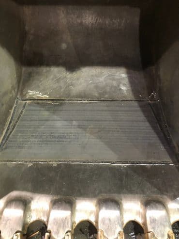 Close-up of a metal surface with visible grooves and welds, likely part of industrial equipment.