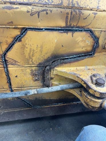 Welded metal repair on a heavy machinery component showcasing detailed craftsmanship.