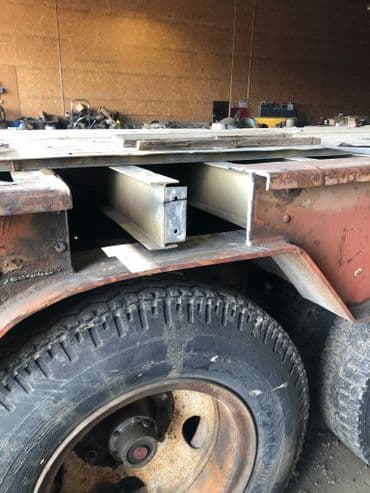 Metal frame construction on a truck bed, showcasing exposed materials and tire details.