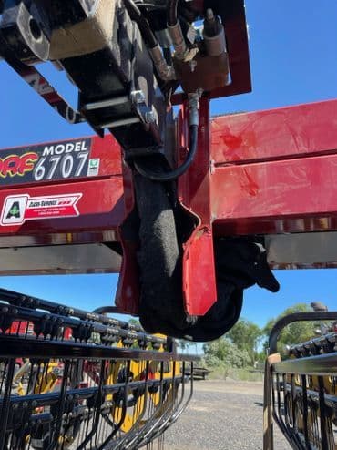 Close-up of agricultural equipment model 6707 with hydraulic components in bright sunlight.