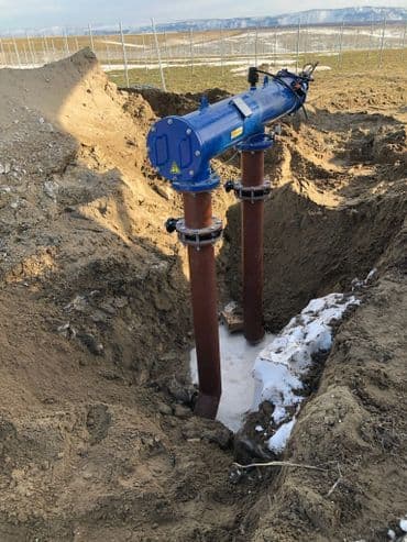 Blue pipeline system installed in a trench, surrounded by dirt and snow, for water management.