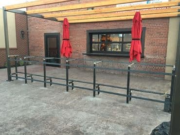Outdoor bar area with red umbrellas and brick wall, featuring a modern design.