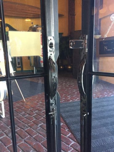 Glass double doors with metallic handles set in a brick walkway entrance.