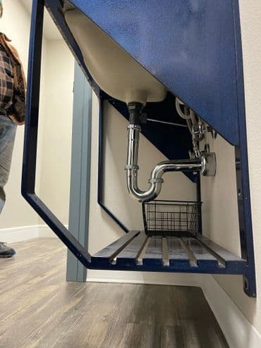 Under-sink plumbing setup with a blue cabinet and metal pipe fittings.