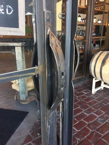 Industrial-style door handle with weathered metal finish at a restaurant entrance.