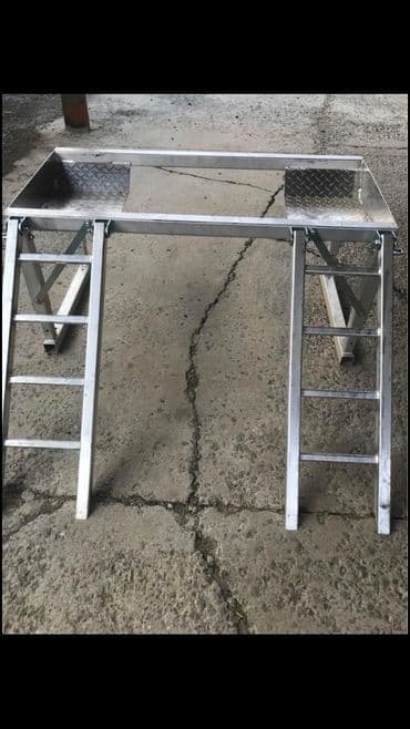 Metal work platform with aluminum frame and ladder sides, ideal for construction tasks.