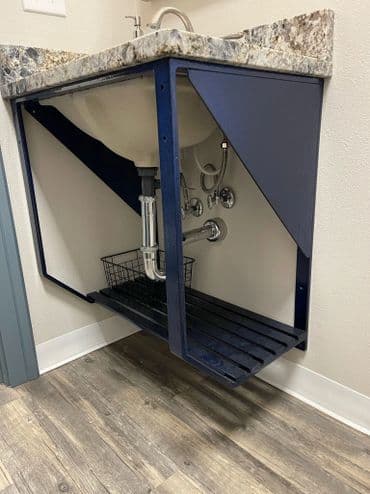 Modern bathroom sink with open cabinet and plumbing, showcasing a sleek design and storage.