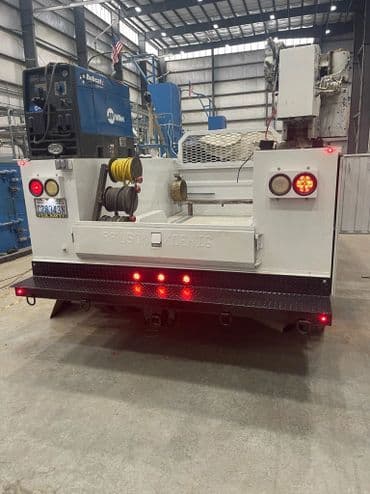 Utility truck in a warehouse with rear lights and equipment visible for maintenance tasks.