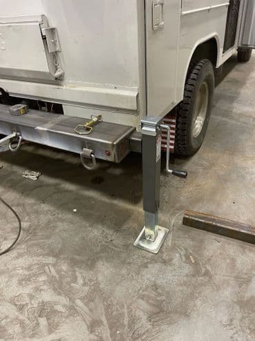 Adjustable support leg installed on a truck's rear for enhanced stability and support.