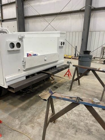 Rear view of an unfinished truck in a workshop, showing metalwork and tools in progress.