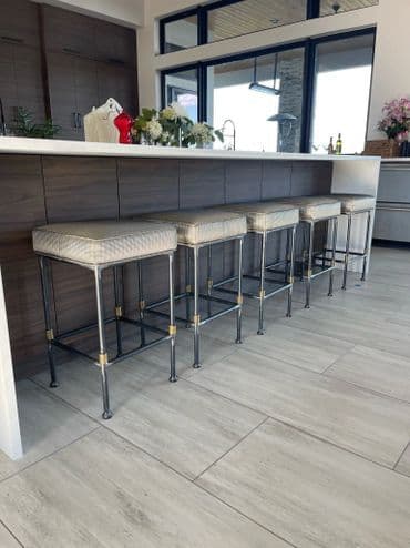 Modern kitchen bar area featuring stylish upholstered stools with metal legs.