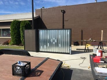 Metal construction gate installation at a commercial building site with tools nearby.
