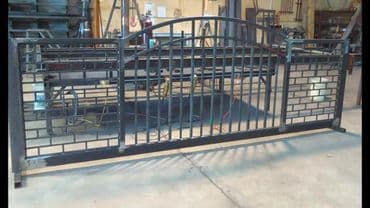 Metal security gate with decorative design, placed in a workshop setting.