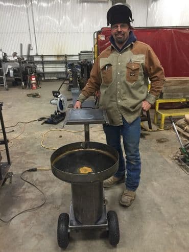 Welding professional with a portable workstation in a workshop environment.