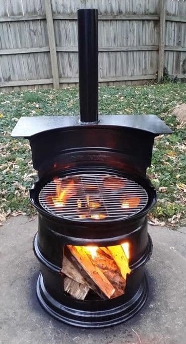 DIY outdoor fire pit made from a metal barrel with a grill and flames. Perfect for cooking and warmth.
