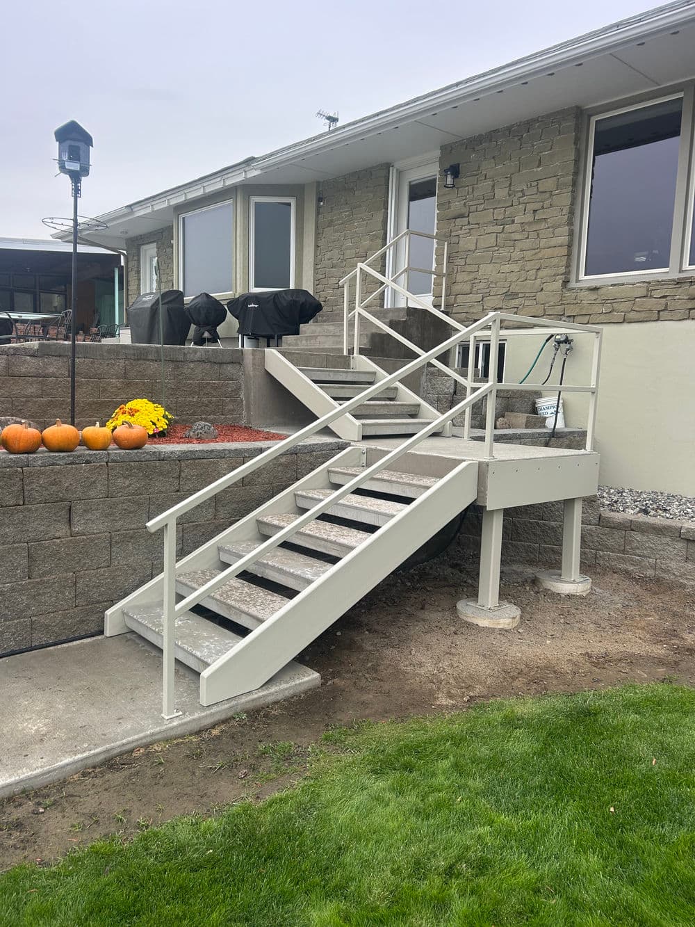 Image of a sturdy outdoor stairway with railings leading to a home, surrounded by landscaping.