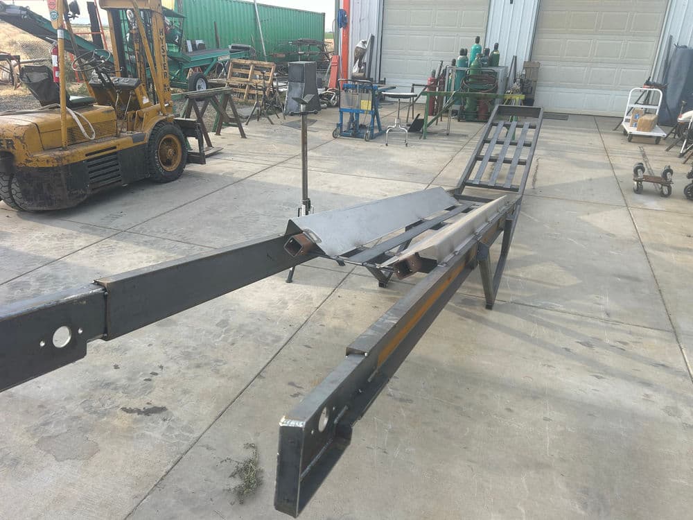 Heavy-duty metal ramp in a workshop with construction equipment in the background.